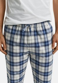 Pantalons de pyjama à carreaux en bleu, gris et blanc ; fabriqués en tissu doux avec une taille élastique et un cordon de serrage adjustable pour plus de confort.