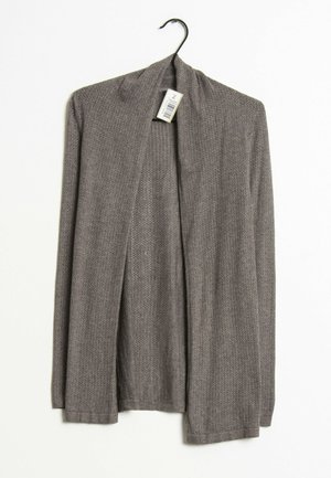 Cardigan gris tricoté à manches longues suspendu à un cintre noir sur fond blanc avec une étiquette de code-barres visible.