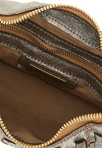 Bustina con zip in oro metallico con esterno metallico liscio e fodera in tessuto beige, con scomparti e un'etichetta del marchio visibile all'interno.