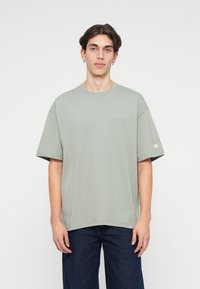 Tricou din bumbac de culoare verde deschis, cu mâneci scurte, decolteu rotund și broderie subtilă a logo-ului pe piept. Purtați-l cu blugi de culoare albastru închis.