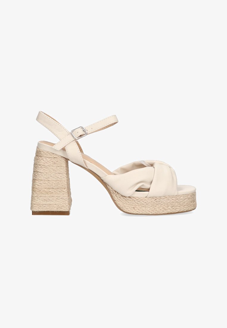 Sandal de tacón alto beige con un detalle anudado, correa de tobillo ajustable y tacón de yute trenzado. Parte superior de sintético suave y suela texturizada.