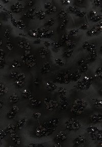 Tissu en maille noir orné de paillettes noires et de perles dispersées, créant une apparence texturée et superposée avec un léger éclat.