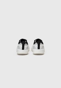 Weiß-graue Sneakers mit einer strukturierten Oberfläche, schwarzen Akzenten und einer Schlaufe zum Anziehen an der Ferse; gepolsterter Schaft für Komfort und Unterstützung.