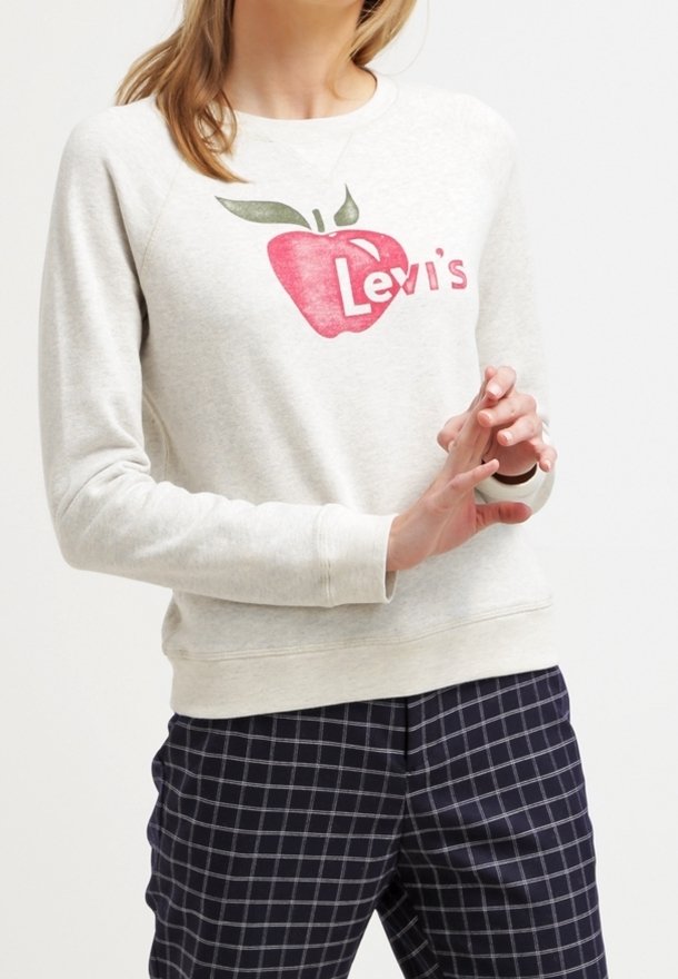Světle šedá mikina s červeným jablkem a nápisem "Levi's". Má kulatý výstřih a žebrované manžety, doplněná tmavě modrými kostkovanými kalhotami.
