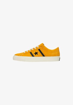 Yellow suede sneaker with black side stripes and star detail. Features white laces and a textured rubber sole. Low-profile design.