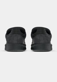 Μαύρα αθλητικά παπούτσια με λείο σουέντ υλικό, επενδεδυμένο περιμετρικό, υφασμένη σόλα και αντίθετες λεπτομέρειες στις πλευρές.