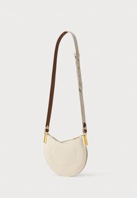 Crèmekleurige leren crossbodytas met een gebogen vorm, bruine verstelbare band en accenten van goudkleurige hardware. Heeft een getextureerd oppervlak en ritssluiting.