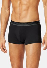 Slip en coton noir avec une taille douce arborant un logo gris discret. Texture lisse, design ajusté avec une couvrance mi-cuisse.