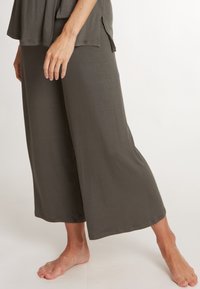 Losse, wijde broek in olijfgroene stof. Zachte textuur met een gladde afwerking, met een ontspannen pasvorm. Geen zichtbare patronen of hardware.