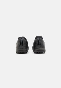 Black athletic shoes with a textured synthetic upper, rubber sole, and distinct heel support. Visible branding on the back.