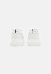 Sneaker in pelle bianca con finitura liscia. Presentano dettagli riflettenti in argento sul tallone e suole in gomma bianca testurizzata.