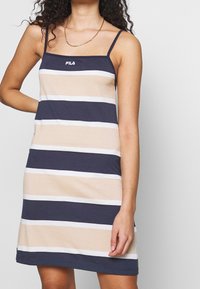Pasiasta sukienka Fila w kolorze granatowym, beżowym i białym; bez rękawów z cienkimi ramiączkami; miękka bawełniana tkanina.