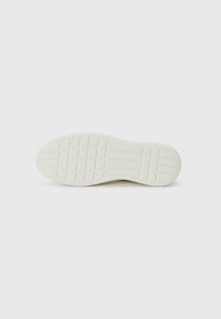 Weiße Schuhsohle mit rechteckigem Profil, glatter Textur und geschwungenem Zehenbereich. Branding im zentralen Bereich sichtbar. Sauberes Design.
