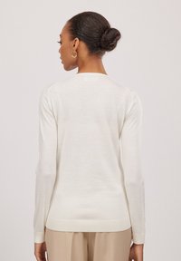 Hellbeige langärmliger Pullover aus weichem Material mit geripptem Saum und Bündchen. Schlichtes Design mit Rundhalsausschnitt und glatter Oberfläche.