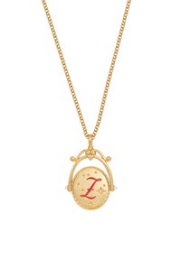 Gouden ketting met een rond hangertje, voorzien van een rode "Z" en kleine steraccenten, omlijst door een beschermende sluiting en pareldetails.