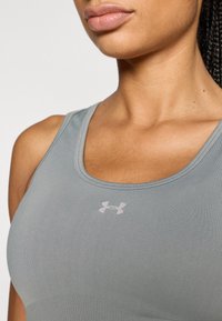 Γκρίζο αθλητικό σουτιέν με ομαλή υφή, με λαιμόκοψη σκούπας και μικρό λευκό λογότυπο Under Armour στο στήθος.