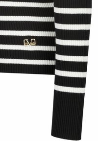 Gestreifter Ripppullover in Schwarz und Weiß mit einem goldenen Logodetail und figurnahem Schnitt. Die Streifen wechseln sich in der Breite ab.