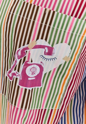 Material w paski w kolorach takich jak zieleń, róż, brąz i pomarańcz. Zawiera grafikę różowego telefonu na sercu, wzmocnioną taśmą.