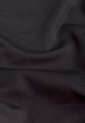 Tissu sombre et lisse avec un motif de tissage diagonal visible et des plis doux créant des ombres subtiles et une texture.