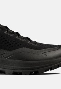 Schwarzer Sportschuh mit strukturierter Sohle, Mesh-Obermaterial und Schnürdesign, gezeigt in Nahaufnahme von der Seite.