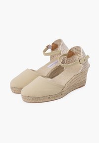 Beige kangastooted espadrillid, millel on pahkluu rihmad, kudumise detailid ja juutkattega taldad. Klassikaline suletud varbaga disain.