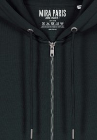 Felpa con zip in cotone verde scuro, con zip argentata, cordini e un'etichetta che recita "MIRA PARIS, BORN TO ROCK". Tessuto testurizzato.
