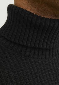 Schwarzer gerippter Rollkragenpullover aus weichem Strickmaterial, mit hohem Kragen und strukturiertem Muster. Nahaufnahme hebt Einzelheiten hervor.