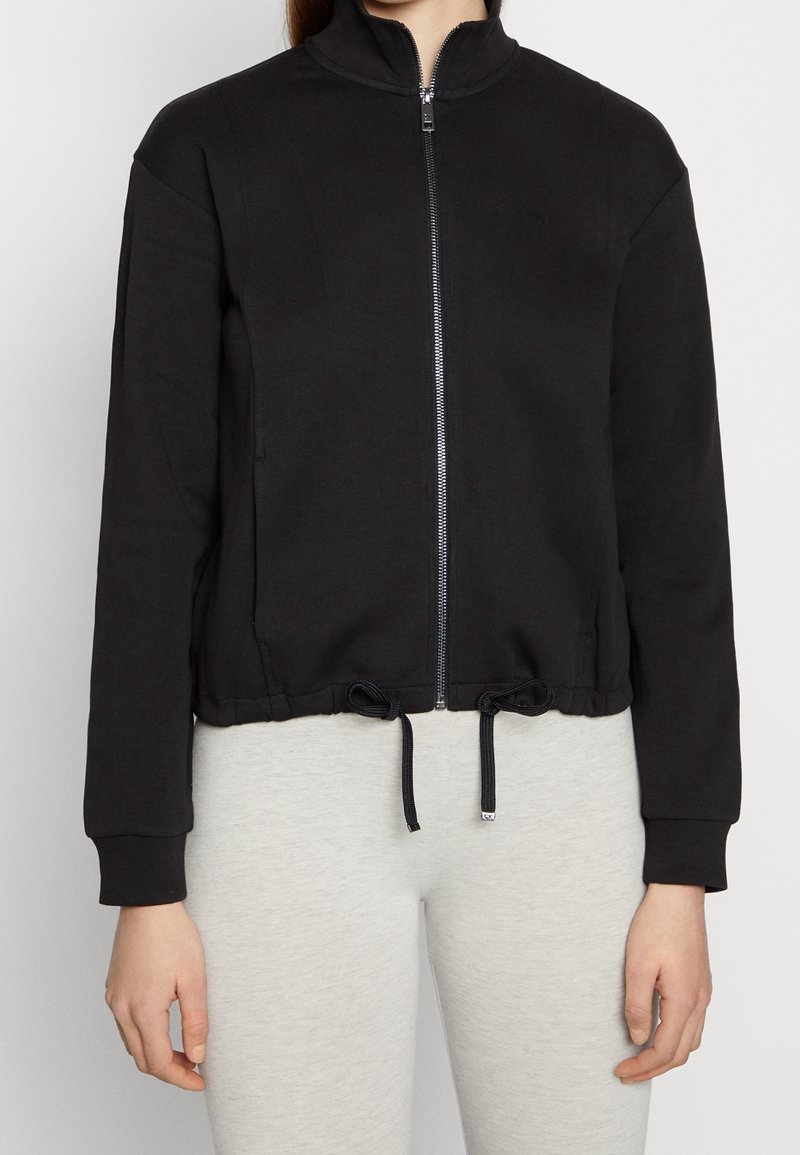 Zwarte rits-hoodie van zacht stof, met een hoge kraag, cropped lengte en verstelbare koord in de taille.