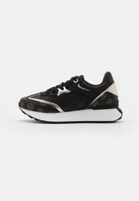 Schwarze Sneaker mit strukturiertem Obermaterial und goldenen Akzenten sowie Logo-Mustern, gepolsterter weißer Sohle und schwarzen Schnürsenkeln.