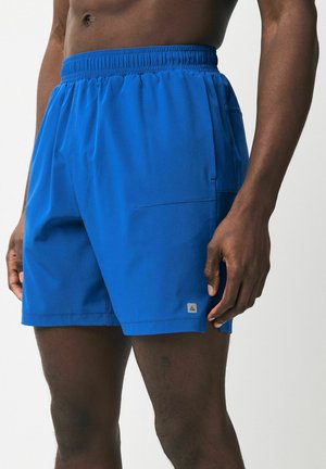 Blå simshorts av lättviktig tyg, med elastisk midja, sidofickor och en liten logotagg på fållen.