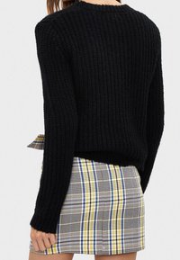 Černý pletený svetr s proužkovanou strukturou. V kombinaci s kostkovanou sukni se žlutými, modrými a šedými vzory.