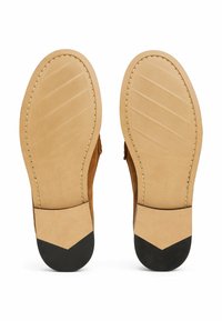 Brown suede shoe soles with beige rubber midsole. Features a textured pattern and black rubber heel accent. Stitch detailing along edges.