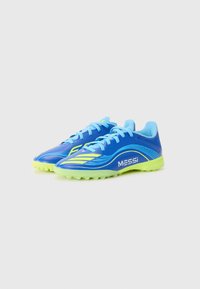 Zapatillas de fútbol azules con acentos amarillos, parte superior de malla y sintético, suela texturizada, con la marca "MESSI" en el lateral.