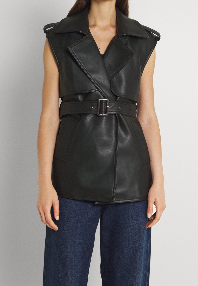 Black leather sleeveless vest with a belted waist, wide collar, and large pockets, featuring a smooth texture and tailored design.
