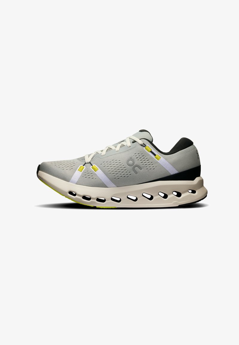 Chaussure de sport grise avec une tige en maille respirante, accents blancs et jaunes, semelle arrondie avec des découpes, et un talon noir texturé.