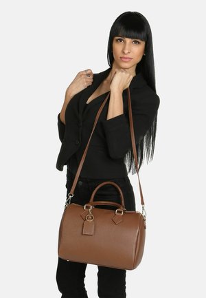 Borsa in pelle marrone con superficie texture, forma rotonda, manici doppi, tracolla regolabile e etichette decorative.