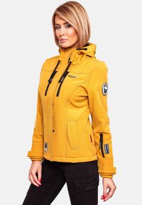 Yellow softshell jacket with a hood, featuring black zippers, pockets, and logo details. Smooth texture and tailored fit.