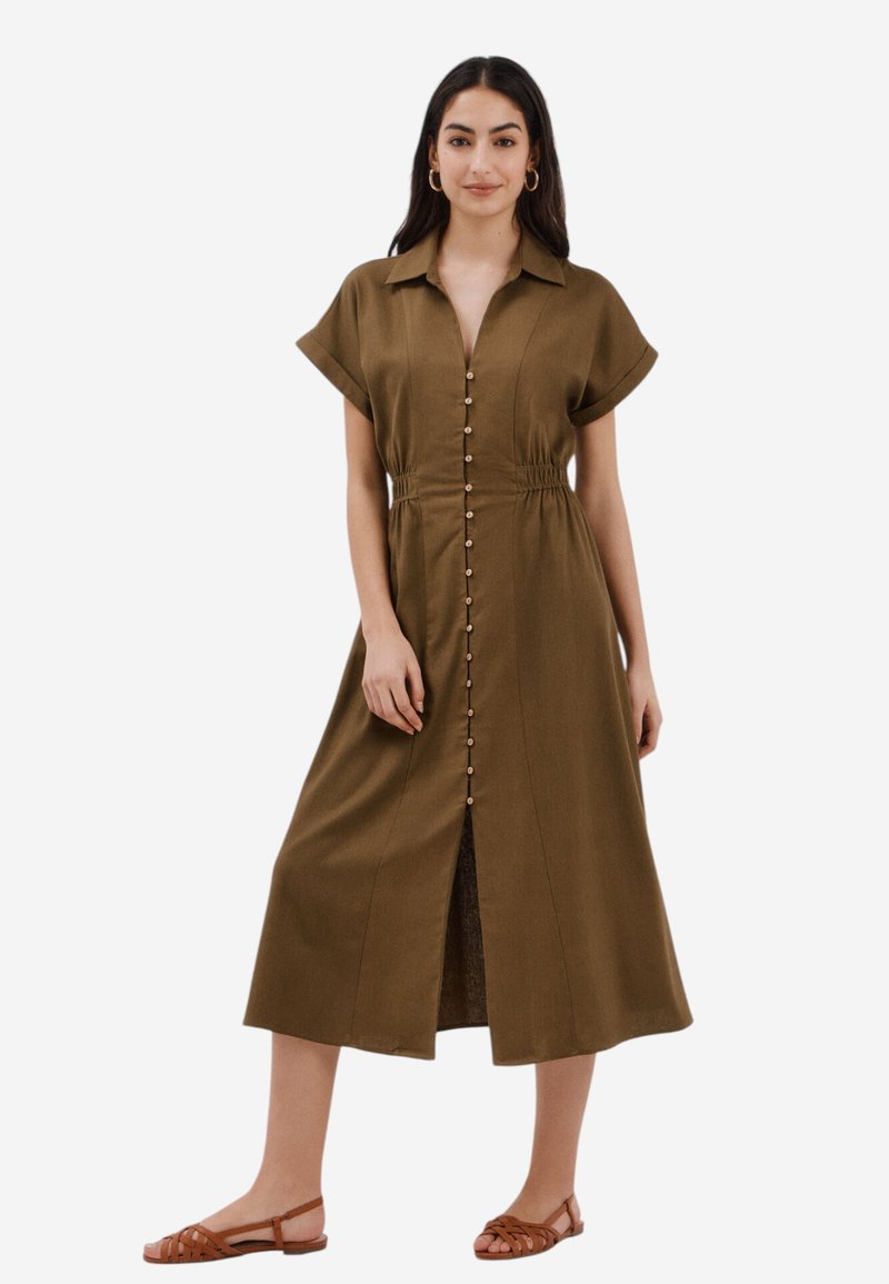 Knielanges, olivengrünes Hemdkleid mit Kragen, kurzen Ärmeln und elastischem Bund. Es hat einen Schlitz vorne und Holzknöpfe.