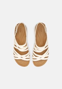 Bílé gumové sandály se spoustou křížových popruhů a polstrovanou béžovou stélkou. Plochý design, vhodné pro volnočasové nošení.