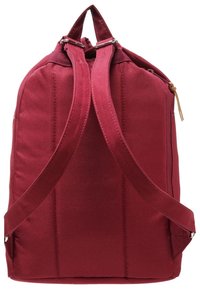Syvänpunainen reppu, jossa on säädettävät pehmustetut olkahihnat ja ylätasku, katsottuna takaa.