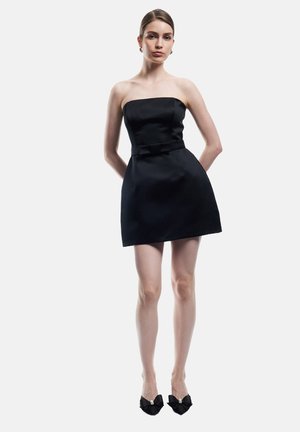 Mustat olkaimettomat minimekot, joissa on istuva bodysuit ja vyötäröllä kaaren muotoinen yksityiskohta, näin saadaan pehmeä pinta ja muotoiltu siluetti.