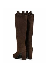 Bottines en suède marron, montantes jusqu'au genou, avec une finition texturée, un sommet incurvé et des talons épais, dotées de poignées à l'arrière pour un enfilage facile.