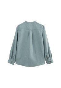 Chemise à manches longues bleu clair, fabriquée dans un tissu doux et texturé. Elle possède un pli dans le dos et des poignets boutonnés pour un ajustement décontracté.
