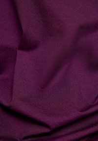 Dunkellila Stoff mit einer glatten, leicht strukturierten Oberfläche. Das Material zeigt sanfte Falten und Knicke, die auf Weichheit und einen schönen Fall hinweisen.