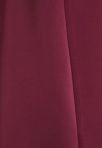 Deux nuances de tissu rouge foncé avec une couture visible courant verticalement entre les sections.