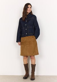 Mörkblå denimjacka med två framfickor, silverknappar och kjol i brunt mocka. Knähöga bruna stövlar fullbordar outfiten.