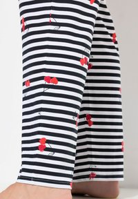 Zwart-witte gestreepte pyjamabroek met rode kersenpatronen. De stof lijkt zacht en licht van gewicht. Afgewerkte manchetten.