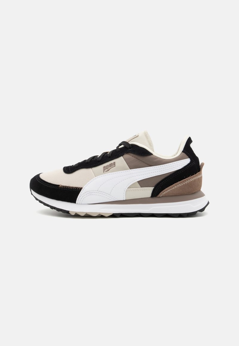 Puma-tennarit, joissa yhdistyy musta, beige ja ruskea materiaali, verkko- ja nappaustekstuurit, nyöri-design ja valkoinen logotunnus.