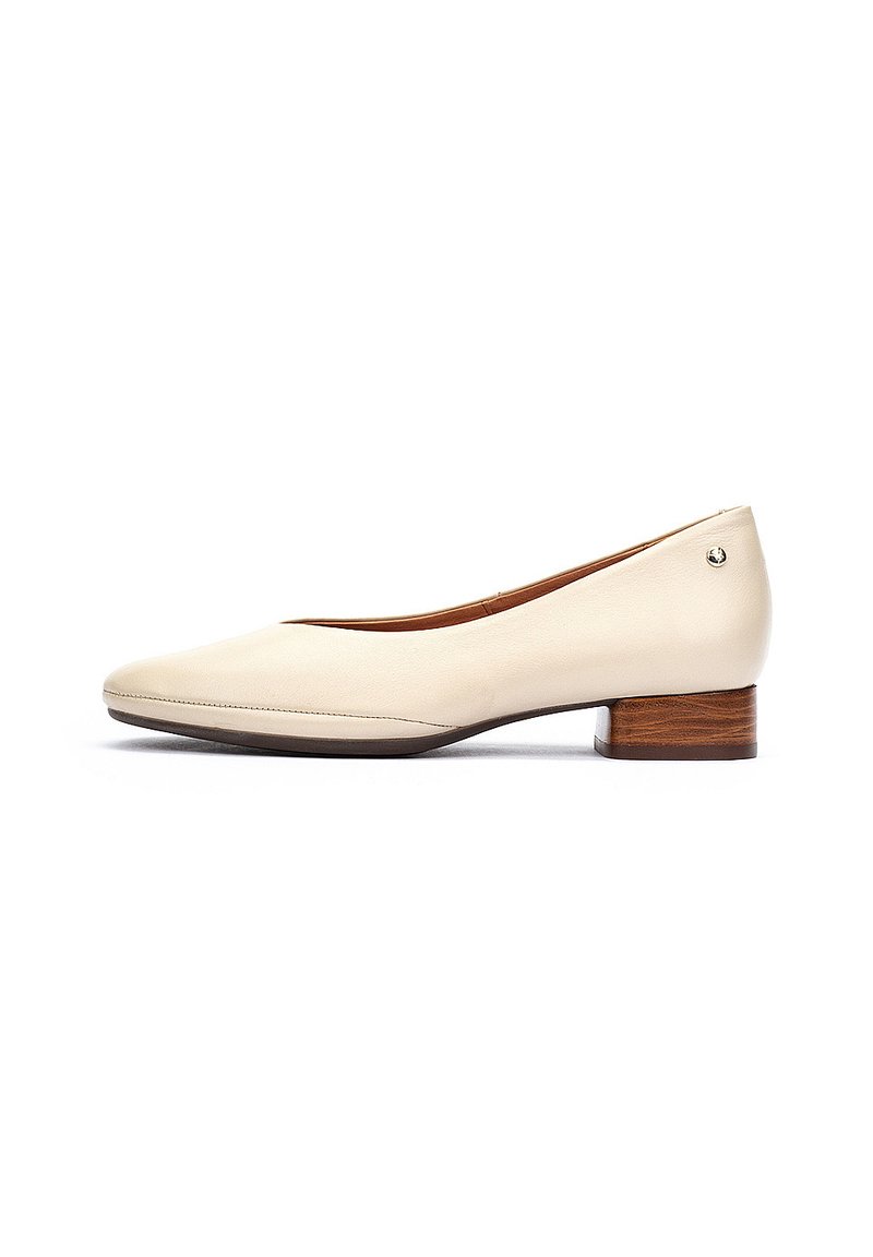 Bailarina de piel beige con punta redonda, tacón bajo de madera y detalle de costura mínima. Textura suave, silueta clásica.