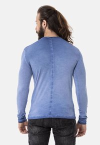 Langärmliges blaues T-Shirt, glatte Textur, Farbverlauf von dunkel nach hell, taillierte Passform, mit minimalen Nähten und Rundhalsausschnitt.